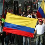 Trabajadores del transporte en Bogotá marchando con banderas de Colombia al lado del Transmilenio